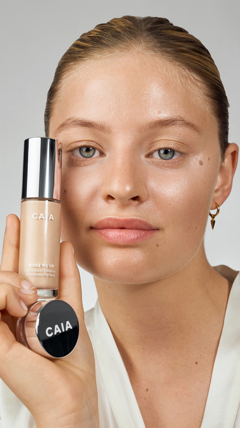 model holding Wake me up complexion enhancer and wake me up cream